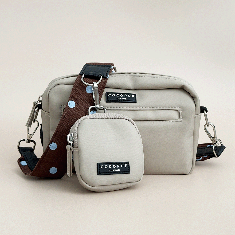 Beige Cocopup Dog Walking Bag, with small pouch for treats attached and also a brown bag strap with blue polka dots.