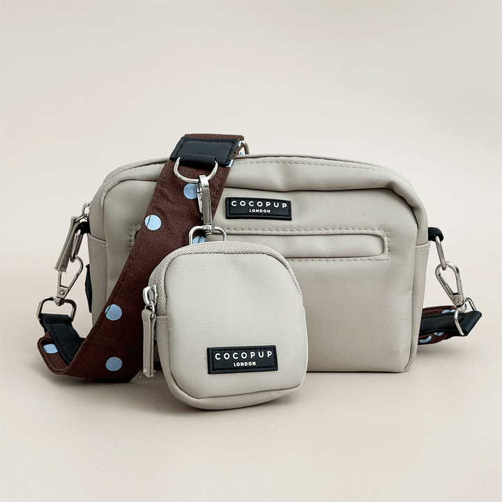 Beige Cocopup Dog Walking Bag, with small pouch for treats attached and also a brown bag strap with blue polka dots.