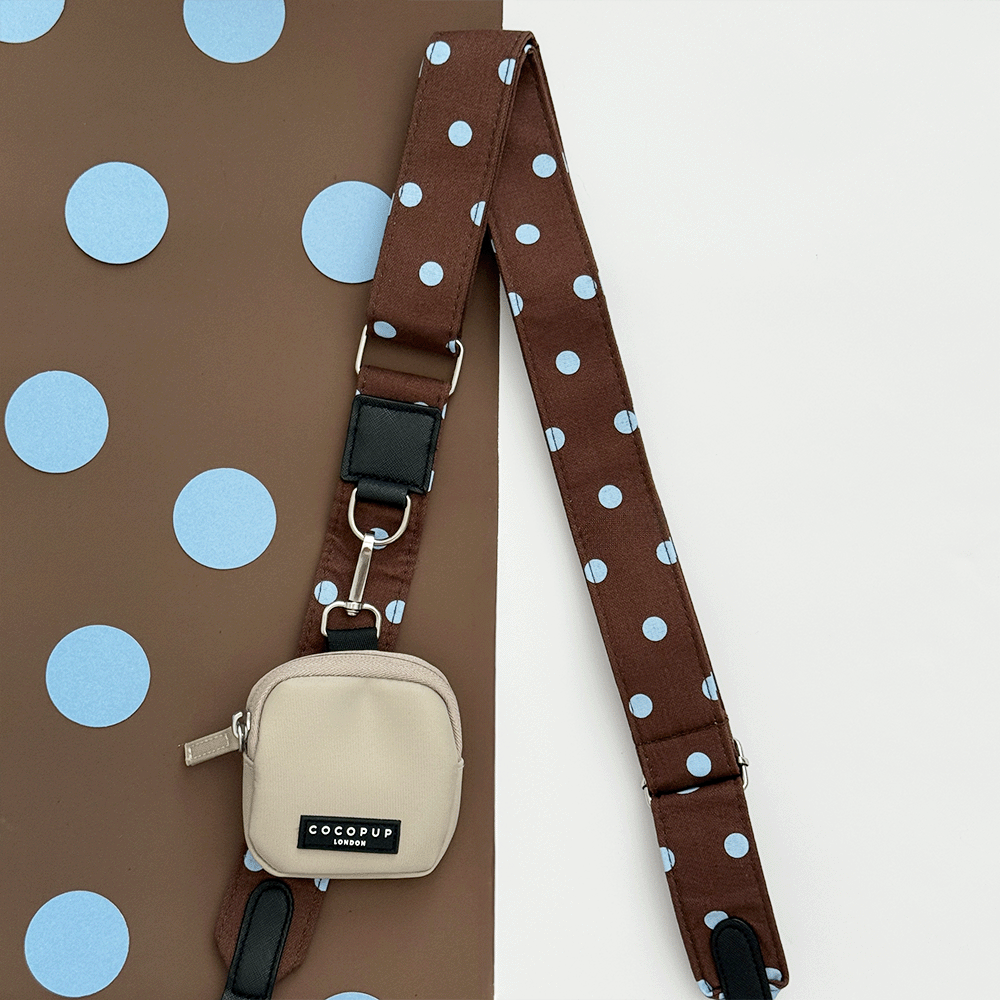 A brown bag strap with light blue polka dot design. Attached is a beige small pouch for dog treats.