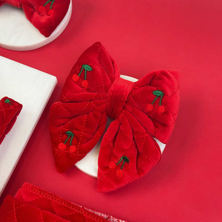 Red bow-shaped hair clips with cherry designs on a red background