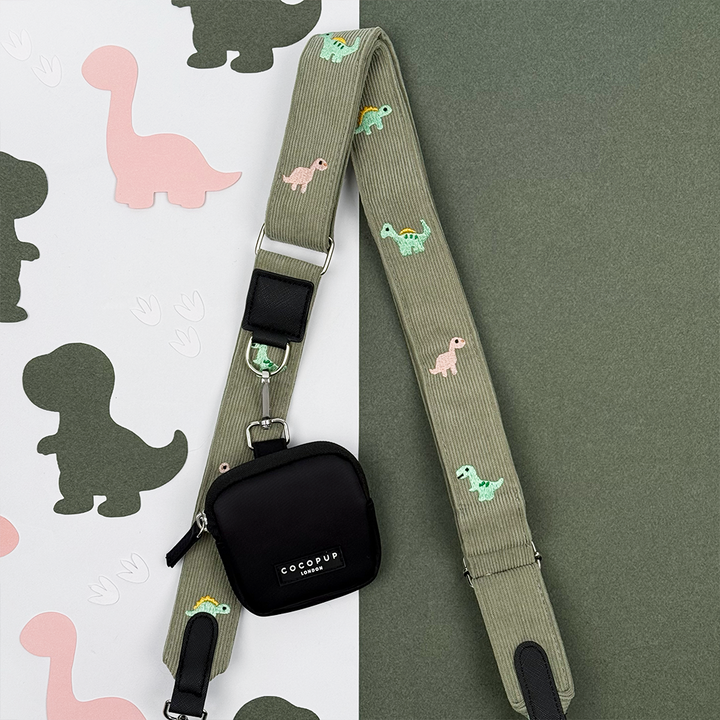 Green corduroy material Bag Strap with embroidered dinosaurs. Attached is a Cocopup London Treat Pouch.