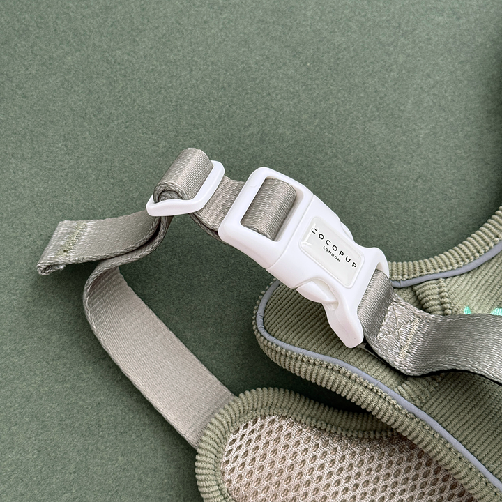 Dog harness in green corduroy material, with embroidered dinosaur design.