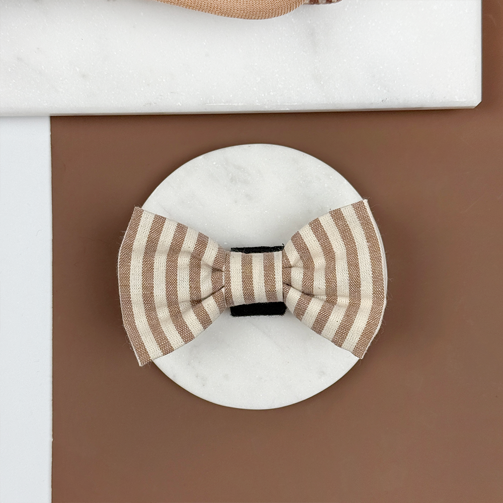Brown and beige striped dog bow tie on a brown background.