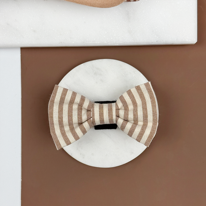 Brown and beige striped dog bow tie on a brown background.