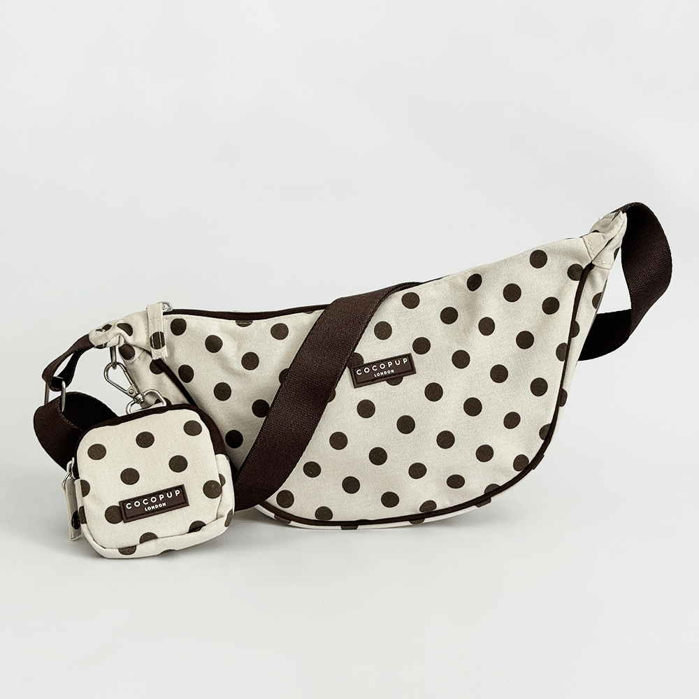 Polka dot crossbody bag with matching pouch on a light gray background