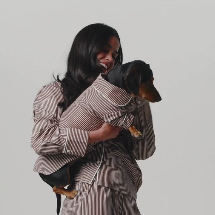 girl and dog in matching brown and white striped PJs